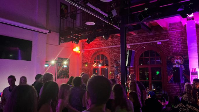 Menschen tanzen und feiern in einem beleuchteten Veranstaltungsort.