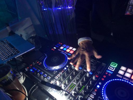DJ steuert Mixer mit bunten Tasten und beleuchteten Effekten.